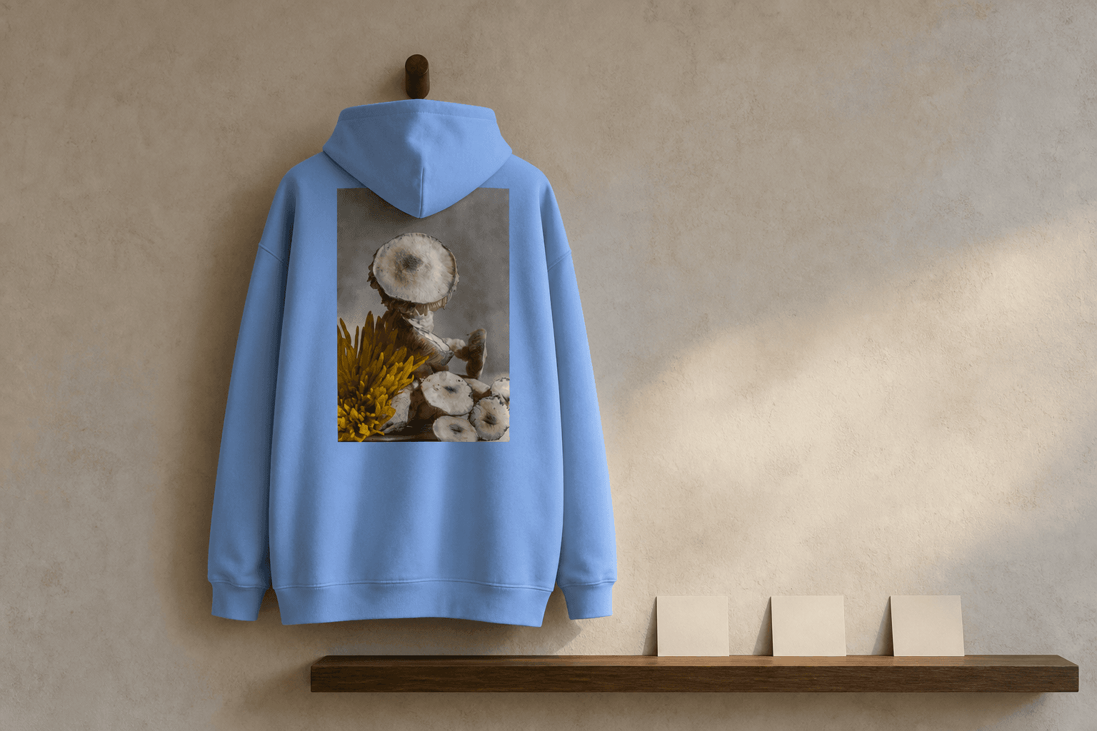 Concept study of the Carolina-blue archive hoodie hanging above a narrow oak shelf